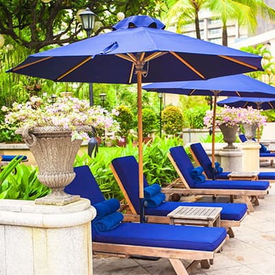 market umbrellas shading deck chairs around a pool with lush greenery in the background