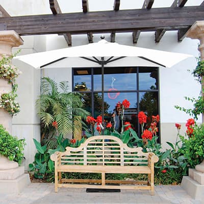 a half wall umbrella shading a bench near a building window