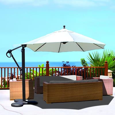 a cantilever umbreella shading a patio seating set by the ocean